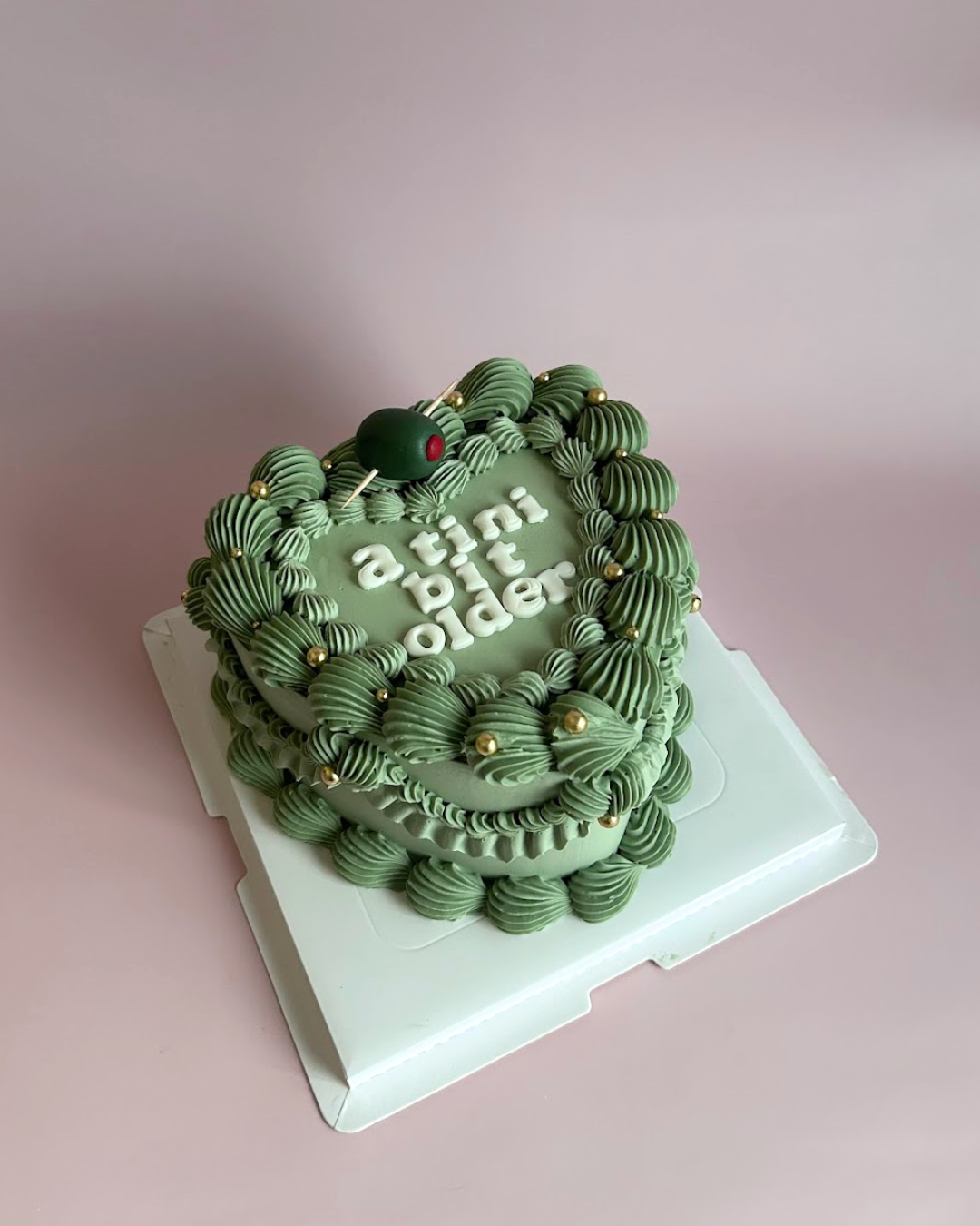 Green Martini cake with 'atlini' branding on a pink background

